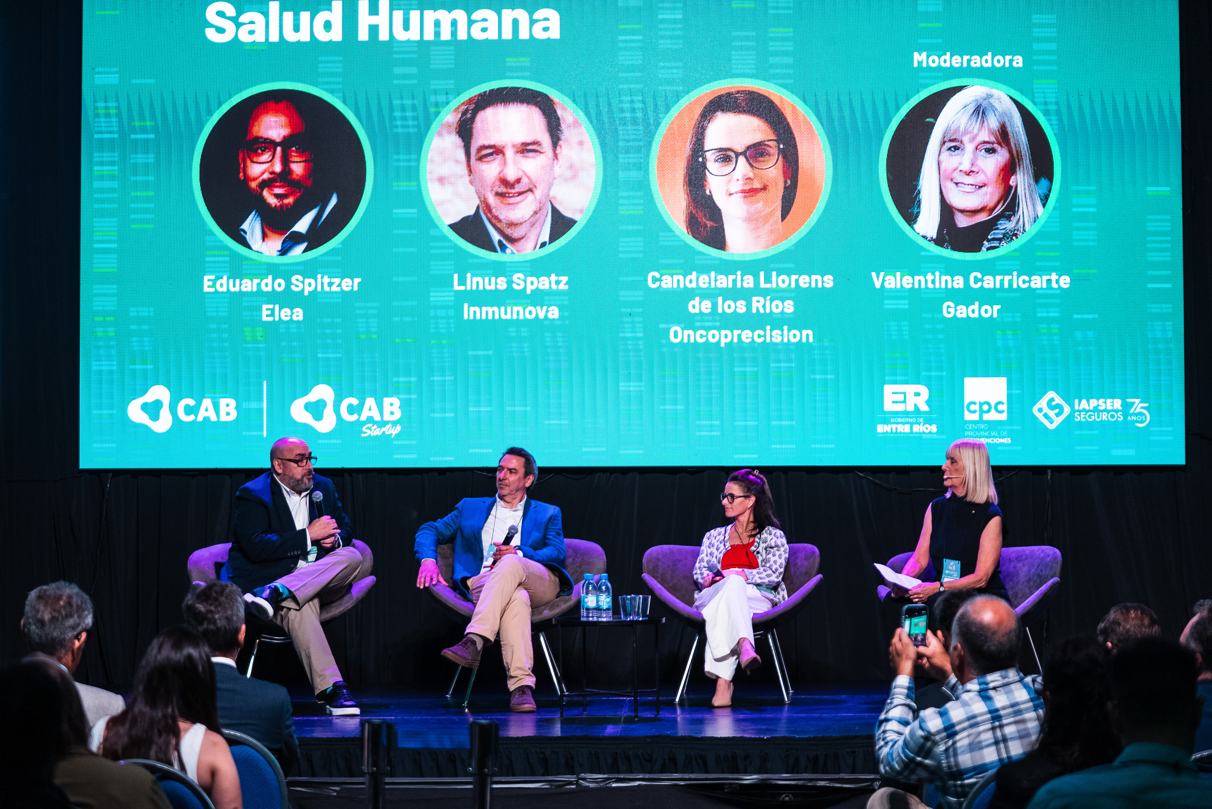Panel de Salud Humana en BioArgentina 2025, con Eduardo Spitzer (Elea), Linus Spatz (Inmunova) y Candelaria Llorens de los Ríos (Oncoprecision), moderado por Valentina Carricarte (Gador), frente a una audiencia en el Centro Provincial de Convenciones de Paraná.